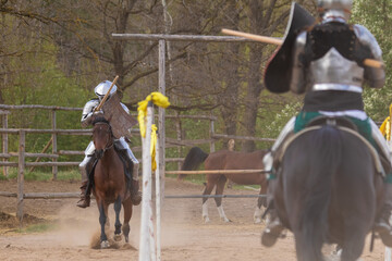 A knight in vintage armor of the 15th century rides a horse across a field for a tournament