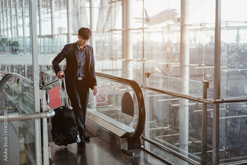 Fotografía Businessman moving to terminal gate by escalator for check in boarding with luggage at the airport