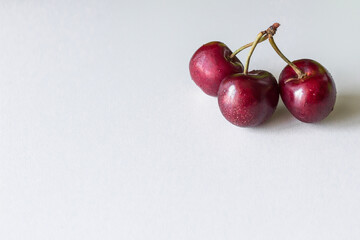 Wall Mural - Several berries on one stalk. Metaphor of treason. Third wheel. Two or three cherries. Vitamins in red fruits. Products on a white background. Healthy summer fruits and berries.