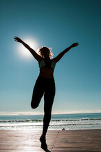 Young Female Dancer Dances At Sunset Wearing Sportswear . Silhouette Backlight Of The Sun With Body Movements. Freedom And Happiness Concept.