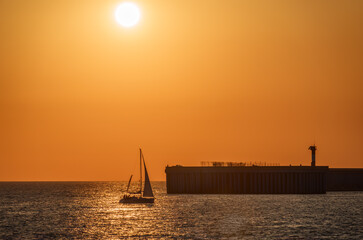 Wall Mural - Beautiful yellow and orange sunset over the sea. The sun goes down over the sea. Silhouette of sea port at sunset