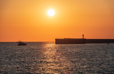 Wall Mural - Beautiful yellow and orange sunset over the sea. The sun goes down over the sea. Silhouette of sea port at sunset