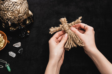 Poster - top view of witch holding voodoo doll near skull and crystals on black