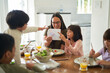 © trevor adeline/Caia Image - Mother and kids eating lunch at dining table