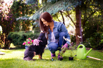 Happy young woman planting flowers in the garden