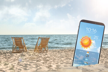 Wall Mural - wooden deck chairs on sandy beach and smartphone with open weather forecast app