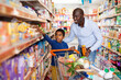 © JackF - Happy friendly African family of father and tween son shopping together in supermarket