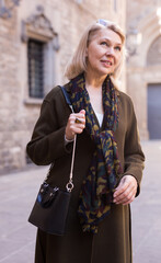 Wall Mural - Portrait of smiling mature woman on street of old european city