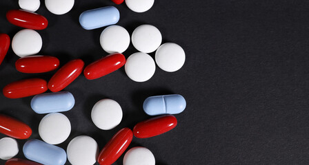 colored pills on a black background. with place for text with the right