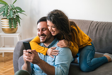 Smiling young couple embracing while looking at mobile phone stock photo