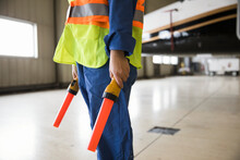 Midsection Of Aircraft Marshaller With Airport Wands Standing In Hangar