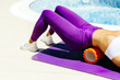 © shevtsovy - sporty woman using Foam Roller massage. Close up of female body on foam roller for self massage doing outdoors on yoga mat.