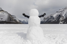 Boy Standing Behind Snowman With Arms Out
