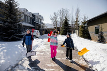 Children Shovelling Snow Outside House