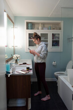 Teenage Girl Using Smart Phone In Bathroom