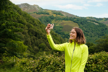 Young woman taking a selfie with her mobile phone after a hike in Asturias