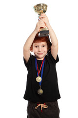 Child athlete winner of the competition. Portrait of a beautiful red-haired boy 5 years old on a white background. A boy with a gold Cup and medals for first place in the competition. Little champion.