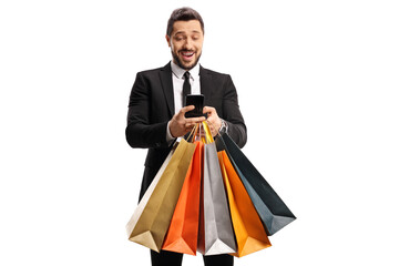 Excited businessman with shopping bags typing on a mobile phone