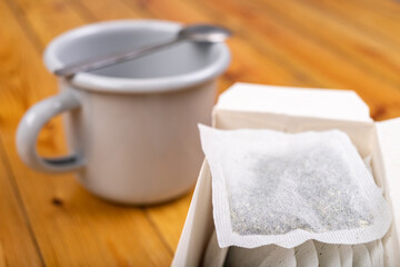 A green tea bag in a cardboard box and a metal mug. Brewing tea in the home kitchen.