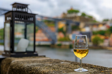 Glass of port wine with the blurred cityscape of Porto Portugal and a lantern in the background