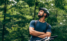 Horizontal Outdoor Image Of Handsome Cyclist Man Resting After Riding Bike In The Mountain. Male Athlete In Cycling Gear Relaxing After Practising Outside In The Forest On Nature Background.