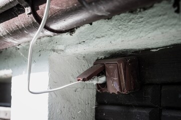 Canvas Print - Closeup shot of a white cable in a brown electrical socket