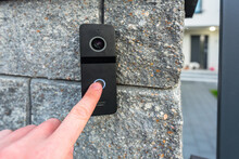 Hand Pressing Button Of Video Intercom Mounted On The Stone Wall