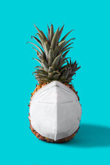 Pineapple with protective face mask on blue background. Summer COVID-19 concept	