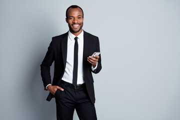 Wall Mural - Portrait of his he nice attractive cheerful cheery chic classy luxury imposing guy employee banker wearing suit holding in hands using device posing isolated over grey pastel color background