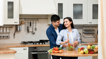 Lovely couple preparing dinner cutting vegetables at their home