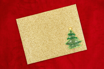 Wall Mural - Blank gold glitter greeting card with Christmas tree on red plush fabric mockup