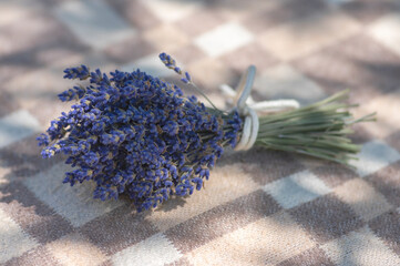 Wall Mural - Lavandula angustifolia bunch of dry flowers in bloom tied with white rope, on checkered textile background in sunlight