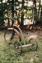 Children's Antique, Rusted Tricycle On Road With Grass
