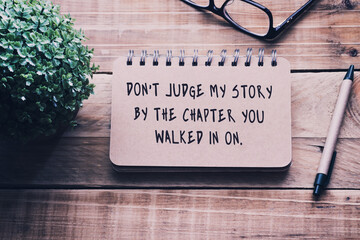 Wall Mural - Inspirational and motivational quotes on a notepad - Don't judge my story by the chapter you walked in on . Blurry retro style background.