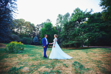 Wedding couple, bride in white wedding dress and groom walking in the woods, dancing and smiling