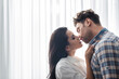 © LIGHTFIELD STUDIOS - Beautiful woman kissing boyfriend near window at home