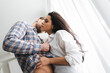 © LIGHTFIELD STUDIOS - Low angle view of woman touching torso of boyfriend near window at home