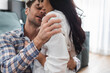 © LIGHTFIELD STUDIOS - Selective focus of man embracing sensual girlfriend in living room