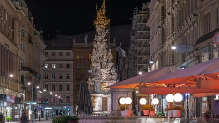 Wall Mural - People is walking in Graben St. night timelapse, old town main street of Vienna with many shops and restaurants, Austria. The column, called The Pestsaule, was inaugurated in 1693 after the end of