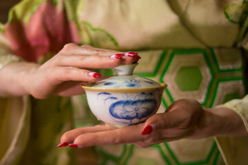 A girl in a green kimono with red manicure holds a white and blue bowl in her hands. Good for restaurants, posters, banners, flyers.
