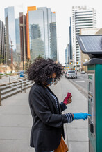 Woman In Face Mask And Glove Using Parking Meter On City Sidewalk