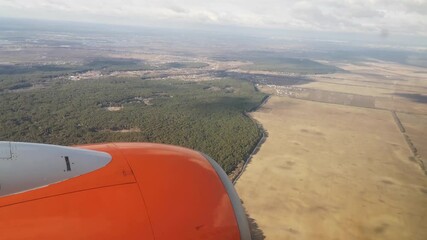 Wall Mural - The plane flies low over an empty autumn-winter field and forest - view from the window (16). The movement of an orange airplane over the landscapes of Ukraine (Europe)