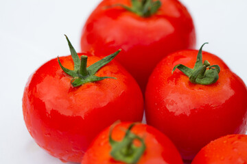 Wall Mural - Details of a red tomato with green stipe and other blurry tomatoes in the background