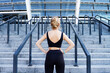 © Monstar Studio - Back view of blonde girl is looking on steps of stadium. Young athletic woman in black tracksuit is preparing for training, climbing on stairs. Daily morning routine. Sport and healthy lifestyle