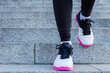 Closeup of athletic female legs in colorful sneakers. Young woman girl is doing exercises, training, jogging, jumping on steps of stadium. Gymnastics outdoor. Sport and healthy lifestyle concept.