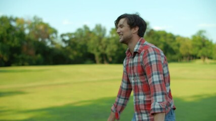 Wall Mural - Man holding ball in hands outside. Smiling guy talking with somebody in park