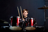 Fototapeta Tęcza - Cheerful smiling child plays the drums. Boys Studios.
