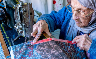 Wall Mural - Arabic muslim woman sewing and measuring lengths with her tape