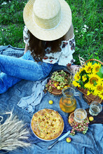 A Young Girl Sits On The Grass In Nature. Picnic Concept