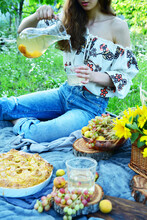 A Young Girl Sits On The Grass In Nature. Picnic Concept